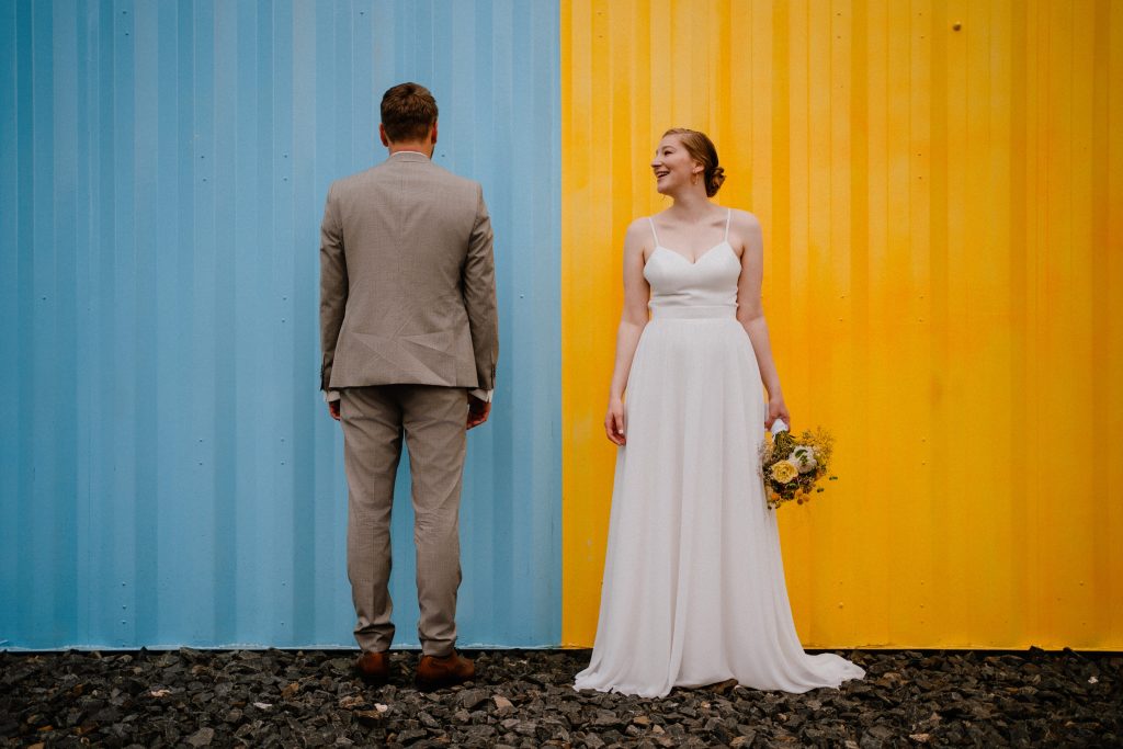 Brautpaar steht vor einer blau gelben Wand