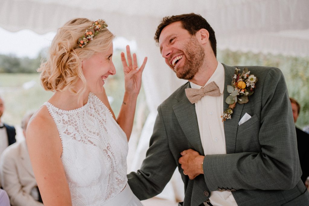 Brautpaar lacht während der standesamtlichen Trauung bei den Hooksieler Skiterrassen
