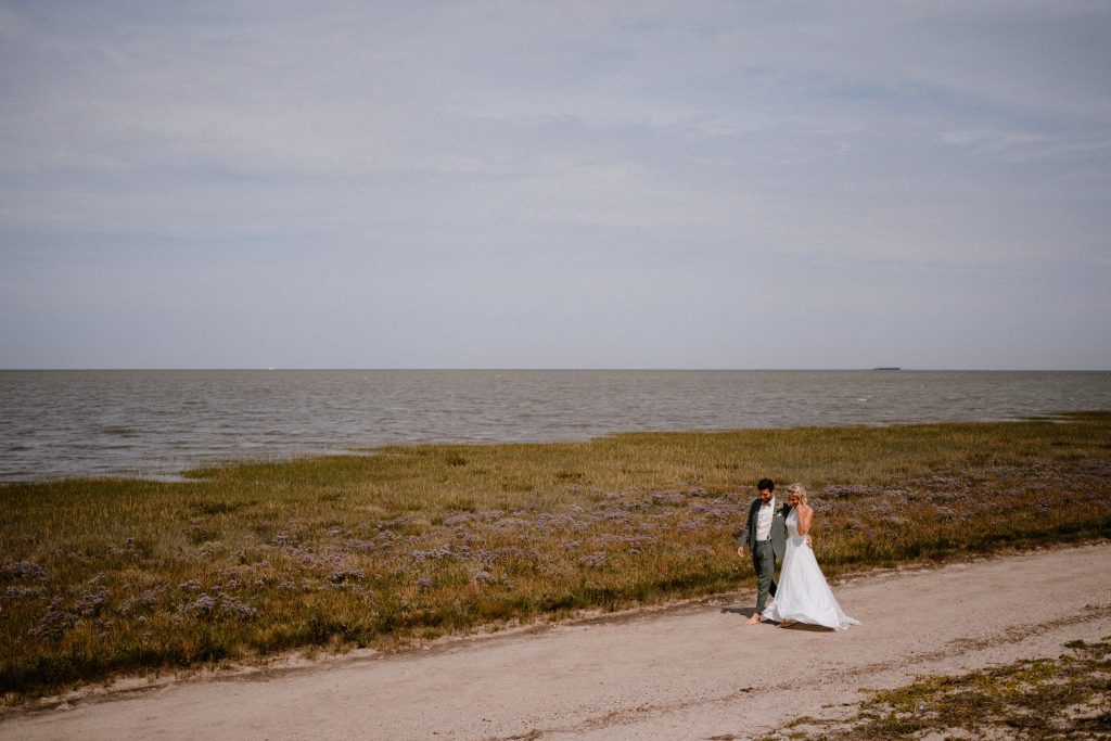 Hochzeitspaar spaziert am Strand von Hooksiel nach der standesamtlichen Trauung