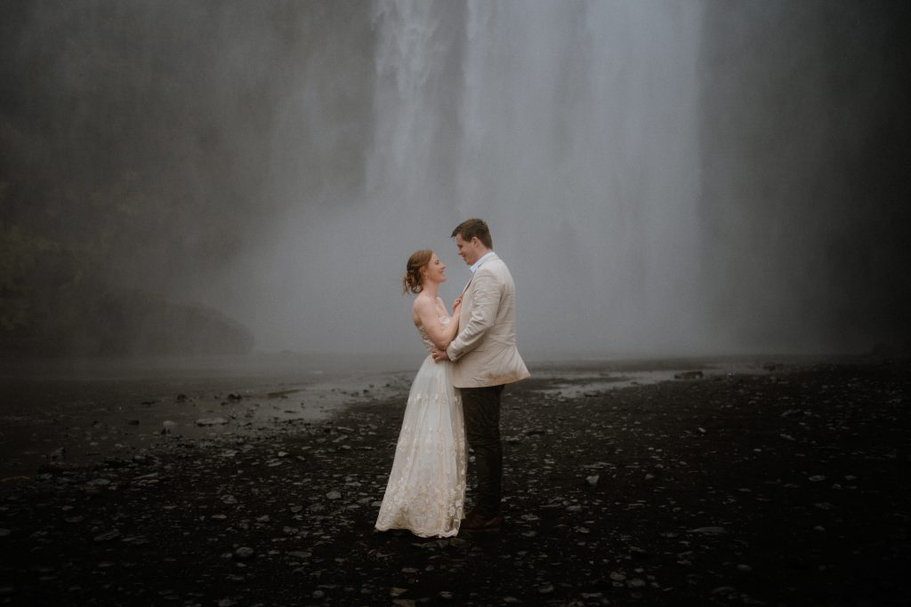 Hochzeitspaar steht vor dem Skogafoss Wasserfall während ihres Elopements in Island