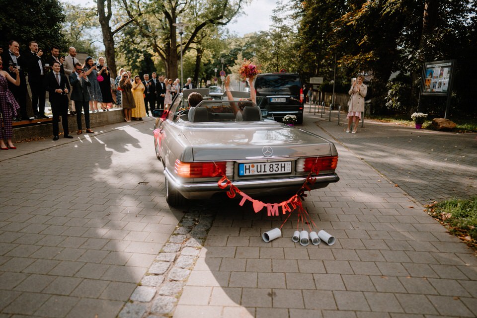 Oldtimer Auto mit Dosen Just Married nach Hochzeit in Hannover vor jubelnden Gästen