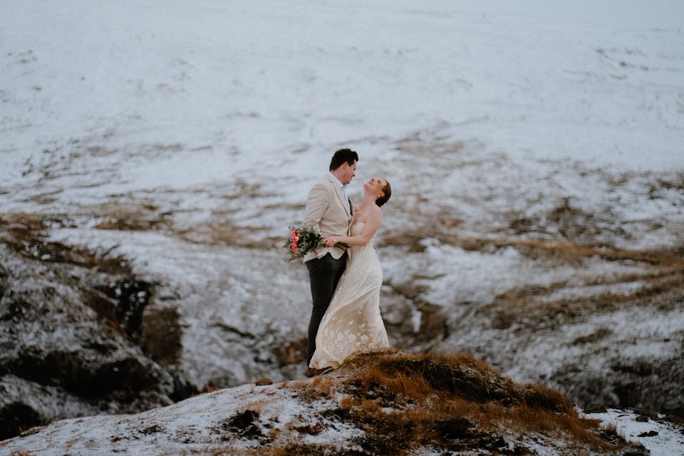 Hochzeitspaar steht auf einem verschneiten Berg während ihres Elopements in Island