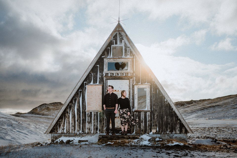 Hochzeitspaar steht vor einer alten Hütte während ihres Elopements in Island